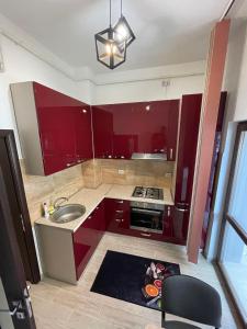 uma cozinha com armários vermelhos e um lavatório em Divine Apartments River Towers em Iaşi