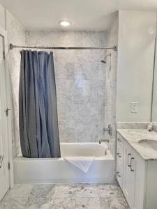 a white bathroom with a tub and a shower at 440-Luxury Apt Near Light Rail in Hoboken