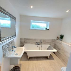 a white bathroom with a tub and a sink at Stylish Bungalow in Symonds Yat in Hereford