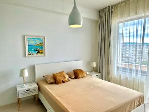 a white bedroom with a bed and a window at Blue Summerland Apartments in Mamaia