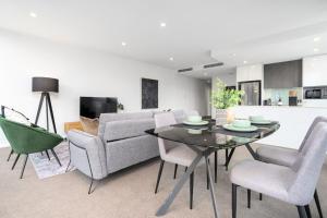 Una sala de estar con un sofá, una mesa y sillas. en Roomy 2BR 2BA City-Centre Apt - Hosted by CanStay, en Canberra