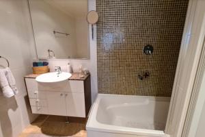 een badkamer met een bad, een wastafel en een douche bij Stunning 2BR Apt in the Heart of Canberra City in Canberra