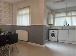 uma cozinha com uma máquina de lavar roupa e uma mesa em Charming 2-BR Property - Sleeps 5 em Warrington