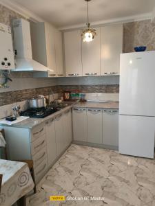 a kitchen with white cabinets and a white refrigerator at Дом для одыха in Tbilisi City