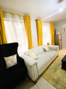 a living room with a white couch and yellow curtains at Feel Home -One bedroom with swimming pool in Kiambu