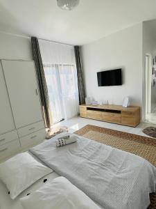 um quarto branco com uma cama e uma televisão de ecrã plano em Apartament zona de case-rezidențiala 2 km de Vivo Mall,curte privata em Baia Mare