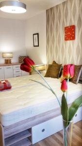 a bedroom with a bed with red flowers in a vase at Apartment in the Heart of Ostrava in Moravská Ostrava