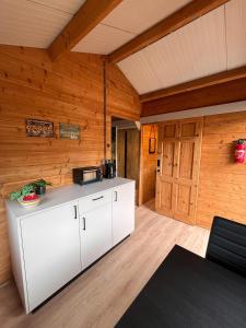 a kitchen with white cabinets in a room with wooden walls at Herberg de Bos in Swalmen