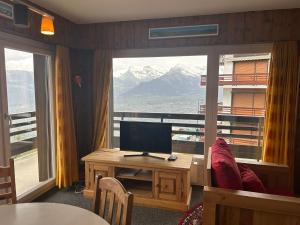 a room with a desk with a television and a window at Combyre COMFORTABLE & CENTER apartements in Veysonnaz