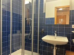 uma casa de banho em azulejos azuis com um lavatório e um chuveiro em Combyre COMFORTABLE & CENTER apartements em Veysonnaz