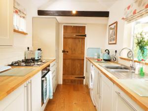 een keuken met witte kasten en een houten aanrecht bij Larksworthy Cottage in North Tawton