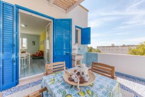 een patio met een tafel en stoelen en blauwe deuren bij Il Carrubo Martella in Gagliano del Capo