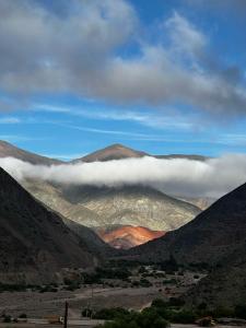 a view of a mountain range with clouds in the valley at Cabañas Bodega Kindgard in Purmamarca
