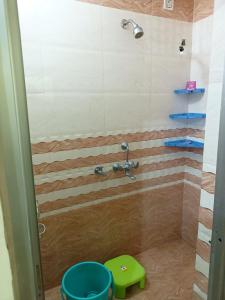 a bathroom with a shower with a green stool at Om Home Stay in Ayodhya