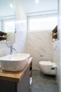 a white bathroom with a sink and a toilet at Seafront Sunset Studio&Rooms in Zadar