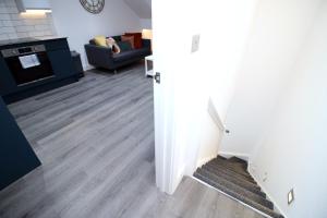 Boutique one bedroom apartment in Cardiff في كارديف: مطبخ وغرفة معيشة مع أرضيات خشبية وأريكة