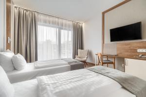 a hotel room with two beds and a flat screen tv at Platino Mare Resort & Spa in Świnoujście
