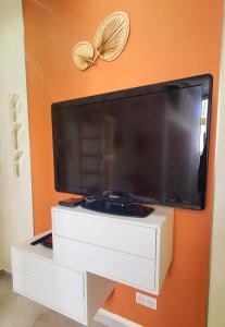 a large flat screen tv on an orange wall at Studio Mezzanine neuf, Monaco à pied, Clim - WIFI in Beausoleil