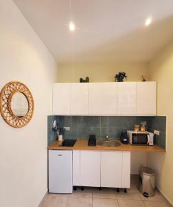 a kitchen with white cabinets and a sink and a microwave at Studio Mezzanine neuf, Monaco à pied, Clim - WIFI in Beausoleil
