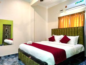 a bedroom with a large bed with red pillows at Naadi Hotel New Busstand Thanjavur in Thanjāvūr