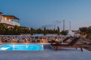 einen Pool mit zwei Liegestühlen neben einem Haus in der Unterkunft Santo Concept Luxury Villas in Agia Anna