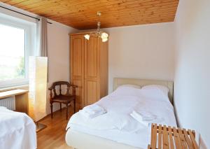 1 dormitorio con cama blanca y techo de madera en 90m² Top Holiday Home Upper Bavaria + Munich South, en Schäftlarn