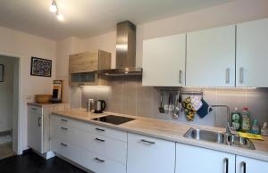 una cocina con armarios blancos y fregadero en 90m² Top Holiday Home Upper Bavaria + Munich South, en Schäftlarn