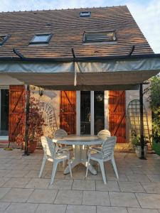 einen Tisch und Stühle unter einem Sonnenschirm auf einer Terrasse in der Unterkunft Chambres à la campagne chez l'habitant in Boissy-sans-Avoir