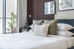 - une chambre avec un lit blanc et des oreillers dans l'établissement GuestReady - Contemporary studio in Business Bay, à Dubaï
