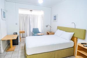 ein Hotelzimmer mit einem Bett und einem Schreibtisch in der Unterkunft Ocean's Edge Lodge Restaurant & Bar in Roseau