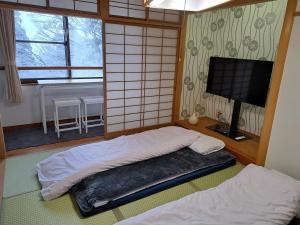 two beds in a room with a television and a room at 大山ベースキャンプ（Daisen Basecamp） in Daisen