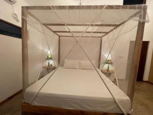 Amba Kola Udawalawa في اوداوالاوي: غرفة نوم بها سرير مظلة مع مصباحين