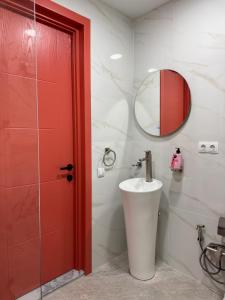 uma casa de banho com um lavatório e uma porta vermelha em hoom100 em Tbilisi