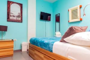 een slaapkamer met blauwe muren en een bed en een televisie bij Bed & Bike Curacao in Willemstad