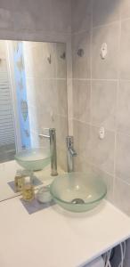 een badkamerbar met een groene wastafel en een spiegel bij Appartement front de mer vue mer 3 personnes + 1 bebe in Hermanville-sur-Mer