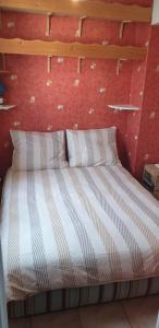 een bed in een kamer met een rode muur bij Appartement front de mer vue mer 3 personnes + 1 bebe in Hermanville-sur-Mer