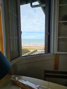 een raam met uitzicht op het strand vanuit een kamer bij Appartement front de mer vue mer 3 personnes + 1 bebe in Hermanville-sur-Mer