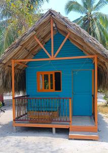 ein blaues Haus mit einem Strohdach am Strand in der Unterkunft Hotel Las Casitas De Mar Adentro in Isla Grande