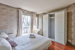 Un dormitorio con una gran cama blanca y una ventana en Appartement grand luxe 180m2, en Neuilly-sur-Seine