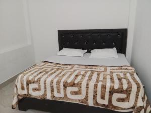 Hotel maa janki palace ayodhya في Ayodhya: سرير مع اللوح الأمامي الأسود والشراشف والوسائد البيضاء
