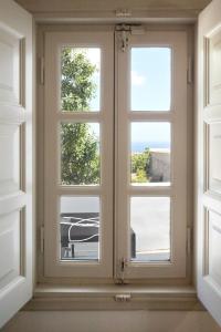 a window with three windows in a room at Angel Santorini Residences in Vourvoulos