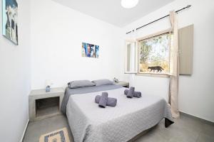 2 camas en un dormitorio blanco con ventana en Angel Santorini Residences, en Vourvoúlos