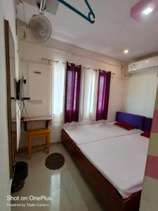 a bedroom with a large bed with purple curtains at FAITH in Siliguri