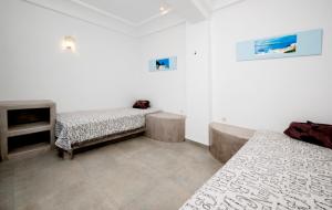 Angel Santorini Residences في Vourvoúlos: غرفة بيضاء مع سريرين ومدفأة