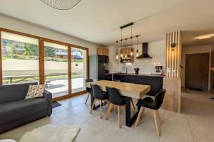 eine Küche und ein Wohnzimmer mit einem Holztisch und Stühlen in der Unterkunft Spacieux appartement au pied des pistes in La Feclaz