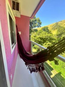 a hammock hanging on the side of a room with a window at Flat Três Praias in Angra dos Reis