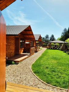 una cabaña de madera con un patio de césped delante de ella en Domki w Dolinie Radomki, 