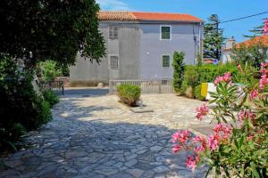 a stone walkway in front of a building with pink flowers at House in Punat on the island of Krk in Punat