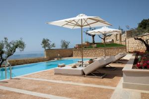 a swimming pool with lounge chairs and umbrellas at Foneas Bay Villa in Proástion