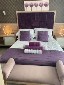 a large bed with purple and white pillows on it at Tattershall VIP Lodge- Lakeside setting with hot tub and private fishing peg situated on Osprey lake tattershall park in Tattershall